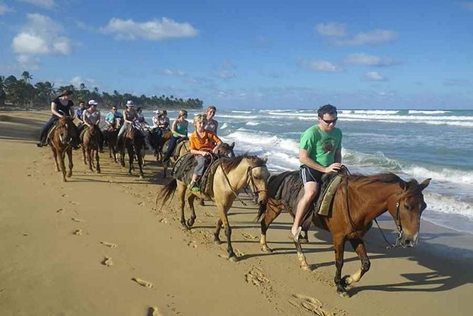 A line of riders on the wet sand at the edge of the sea in Punta Cana